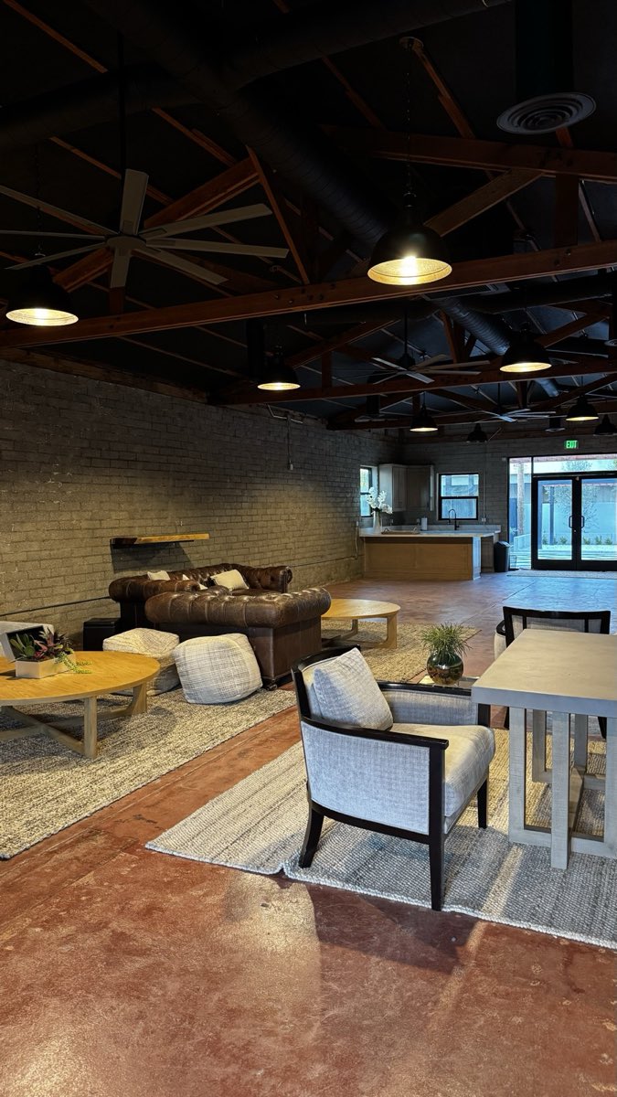 Indoor lounge under exposed timber trusses with pendant lighting, leather sofas, and seating areas