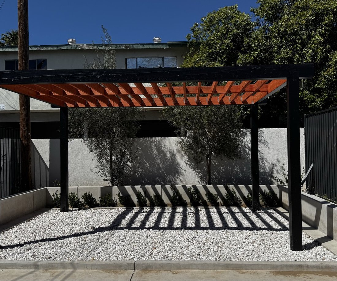 Orange pergola over the outdoor patio on a sunny day, casting striped shadows