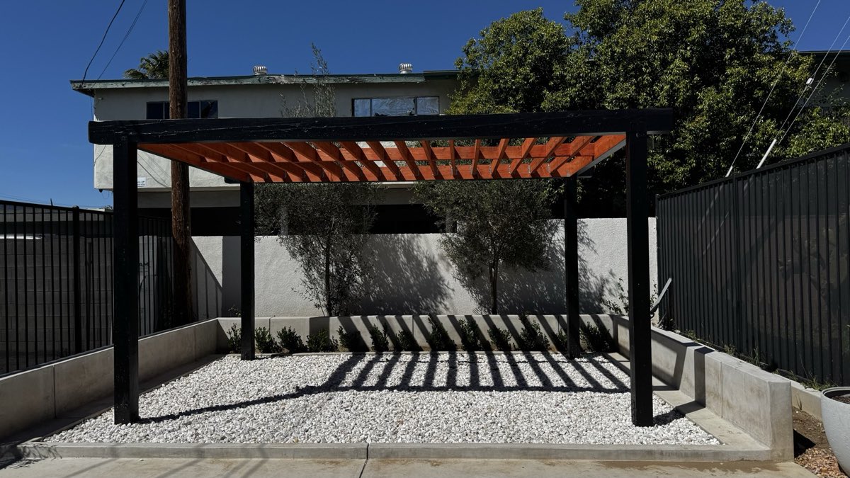 Orange pergola over the outdoor patio on a sunny day, casting striped shadows