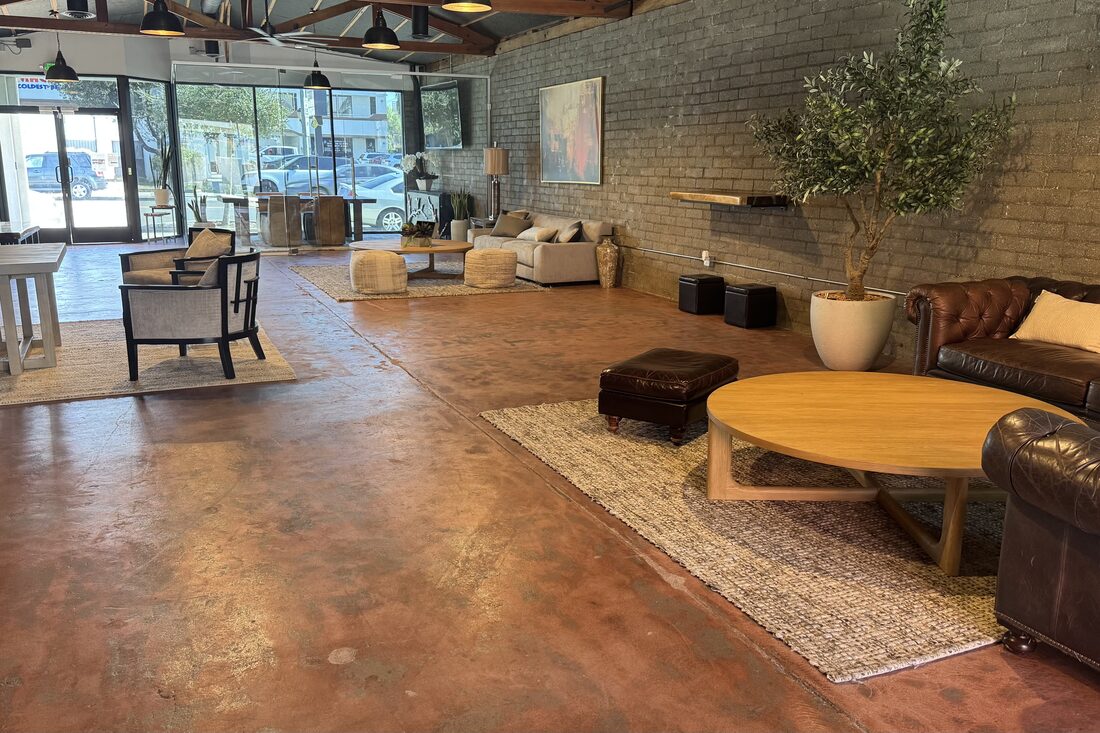 Full length of the room from the leather sofas to the storefront glass entry, with open floor between seating areas